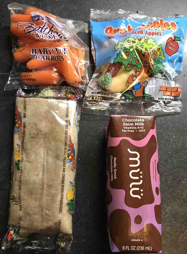 meal containing a burrito, baby carrots, a pouch of apple slices, and a box of UHT chocolate milk